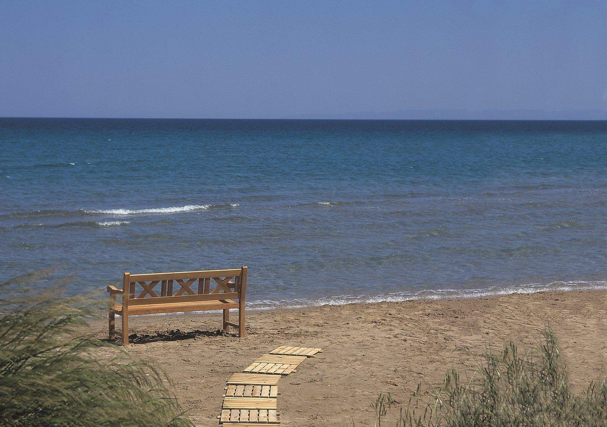 Teak skipper bench with cross-braced back and armrests, angled view
