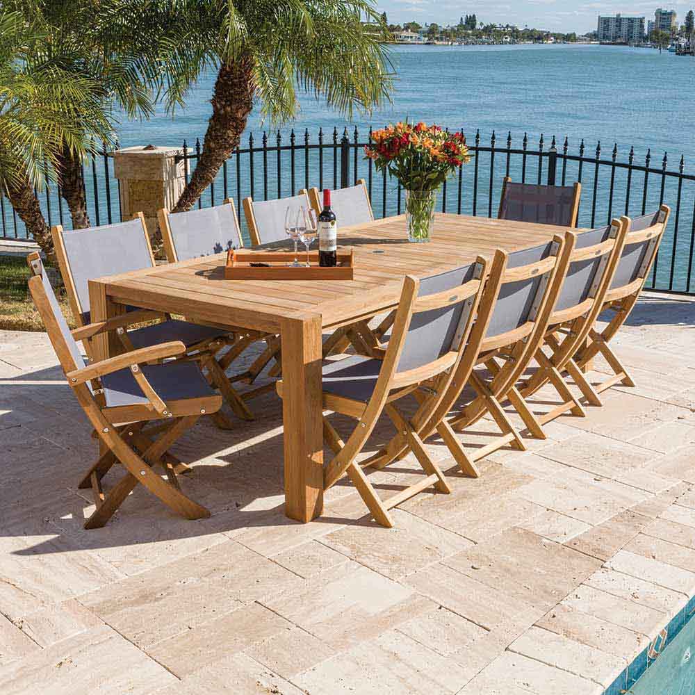 Teak folding arm chair with light sling fabric, shown among patio dining set