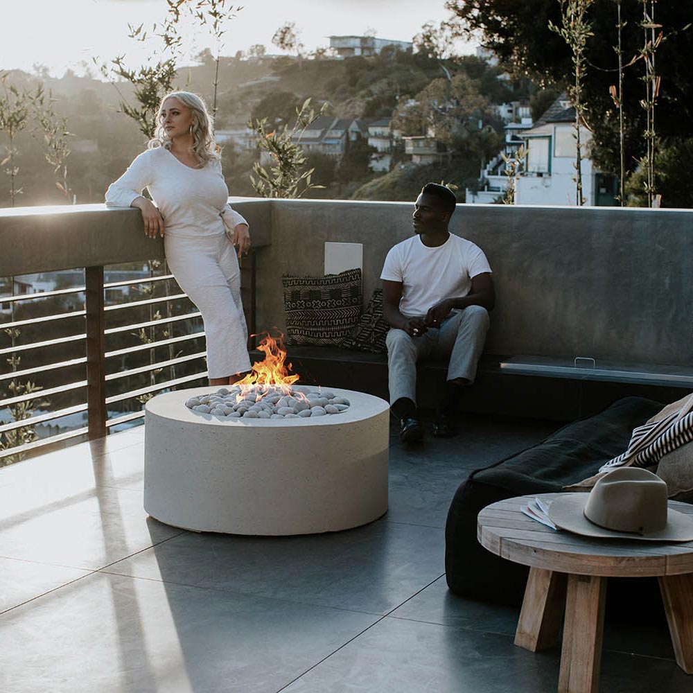 Outdoor lightweight concrete gas fire pit with flame above grey stones