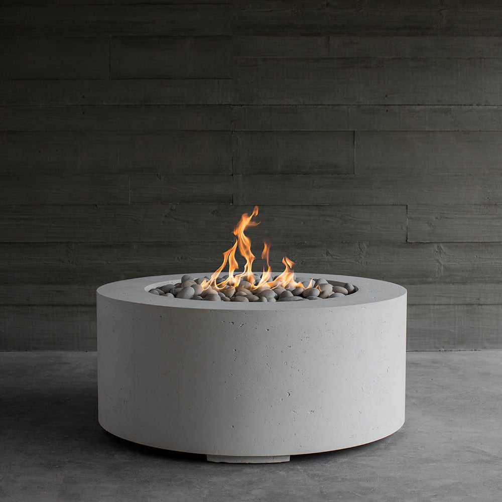 Round lightweight concrete gas fire pit with visible flame in stone-filled bowl