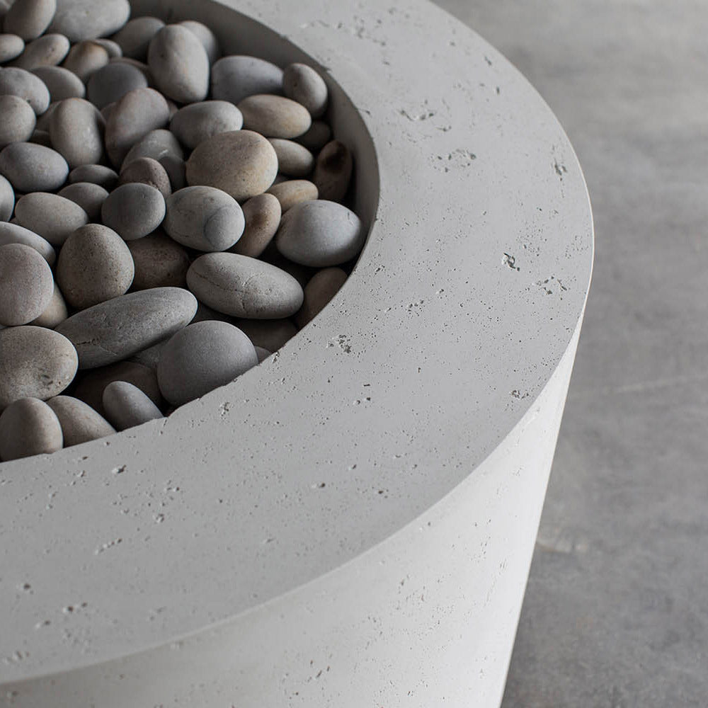 Close-up of lightweight concrete gas fire pit rim with grey river stones