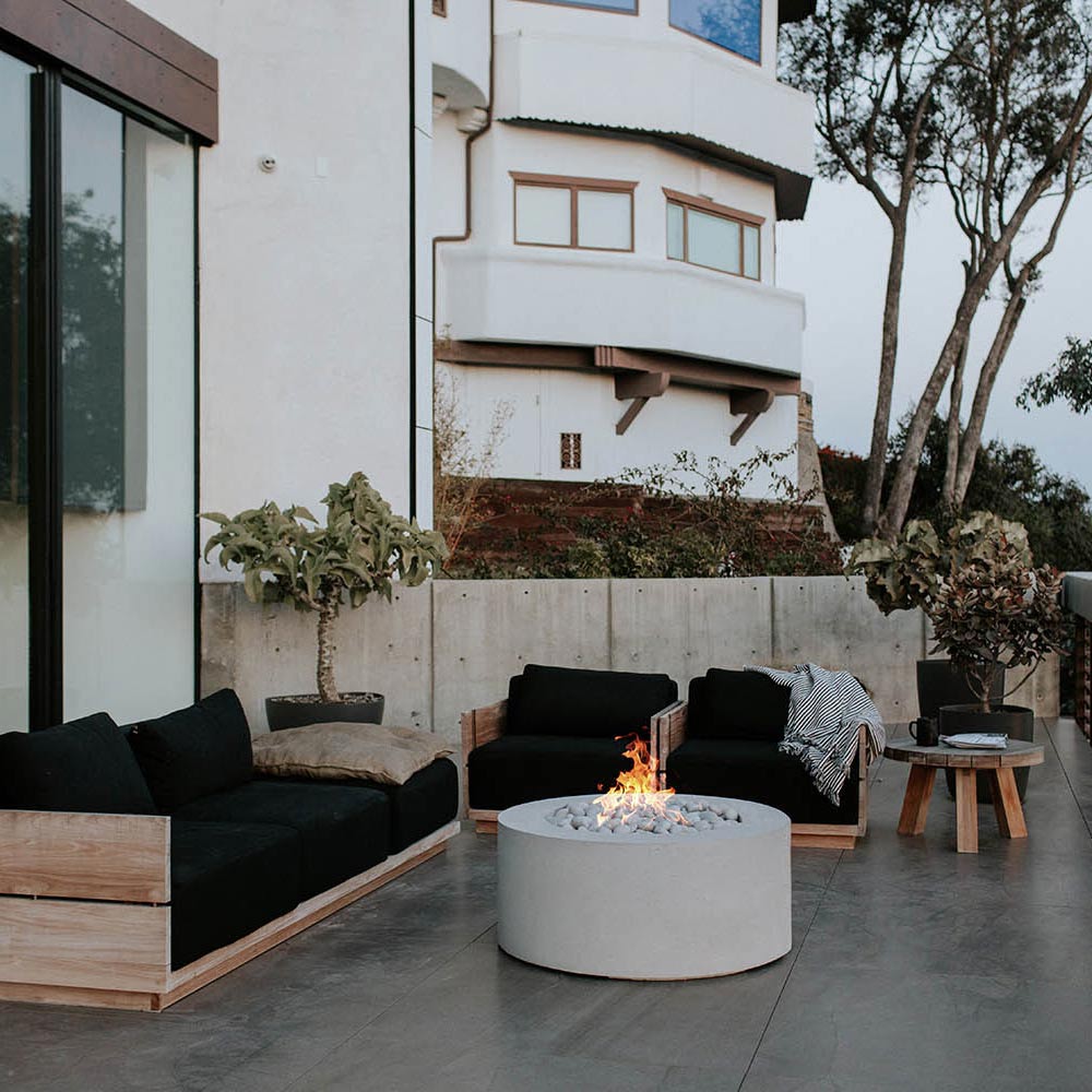 Patio lightweight concrete gas fire pit with flame over grey stones