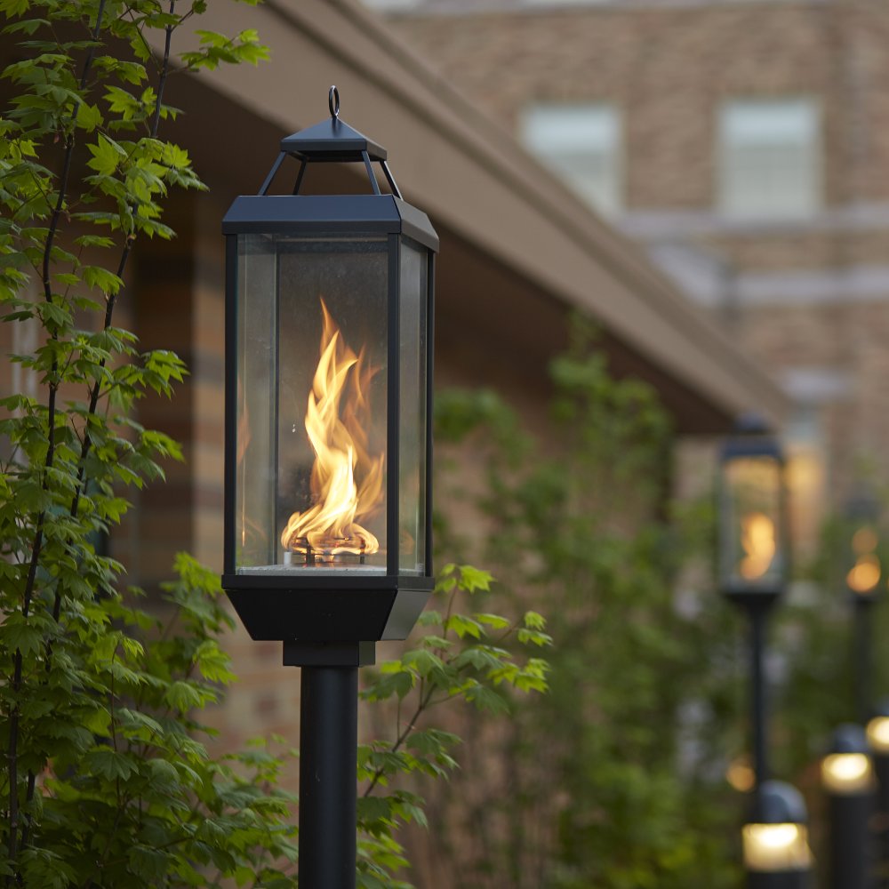 Black deck-mounted gas lantern with flame inside glass housing