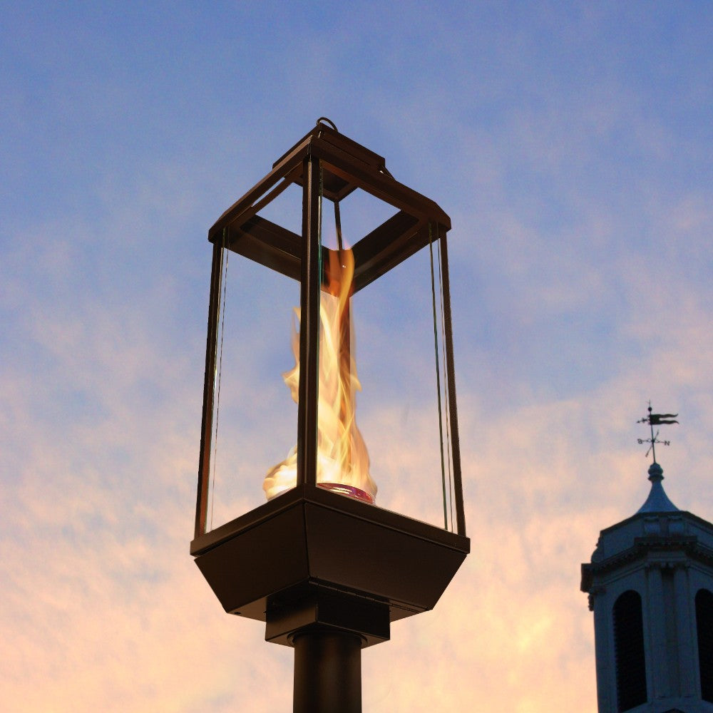 Outdoor gas lantern with hexagonal frame and flame burning inside clear glass