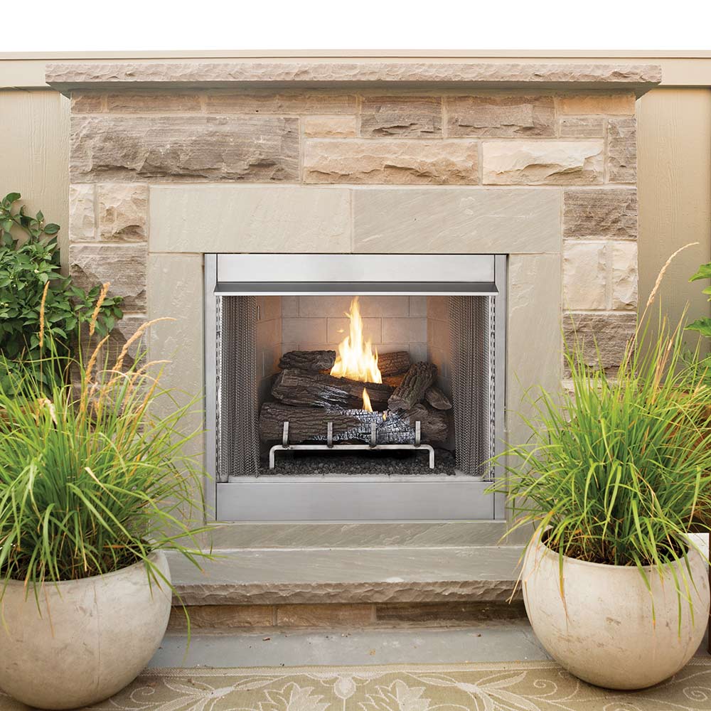 Outdoor vent-free firebox set into stone wall with burning flames and logs