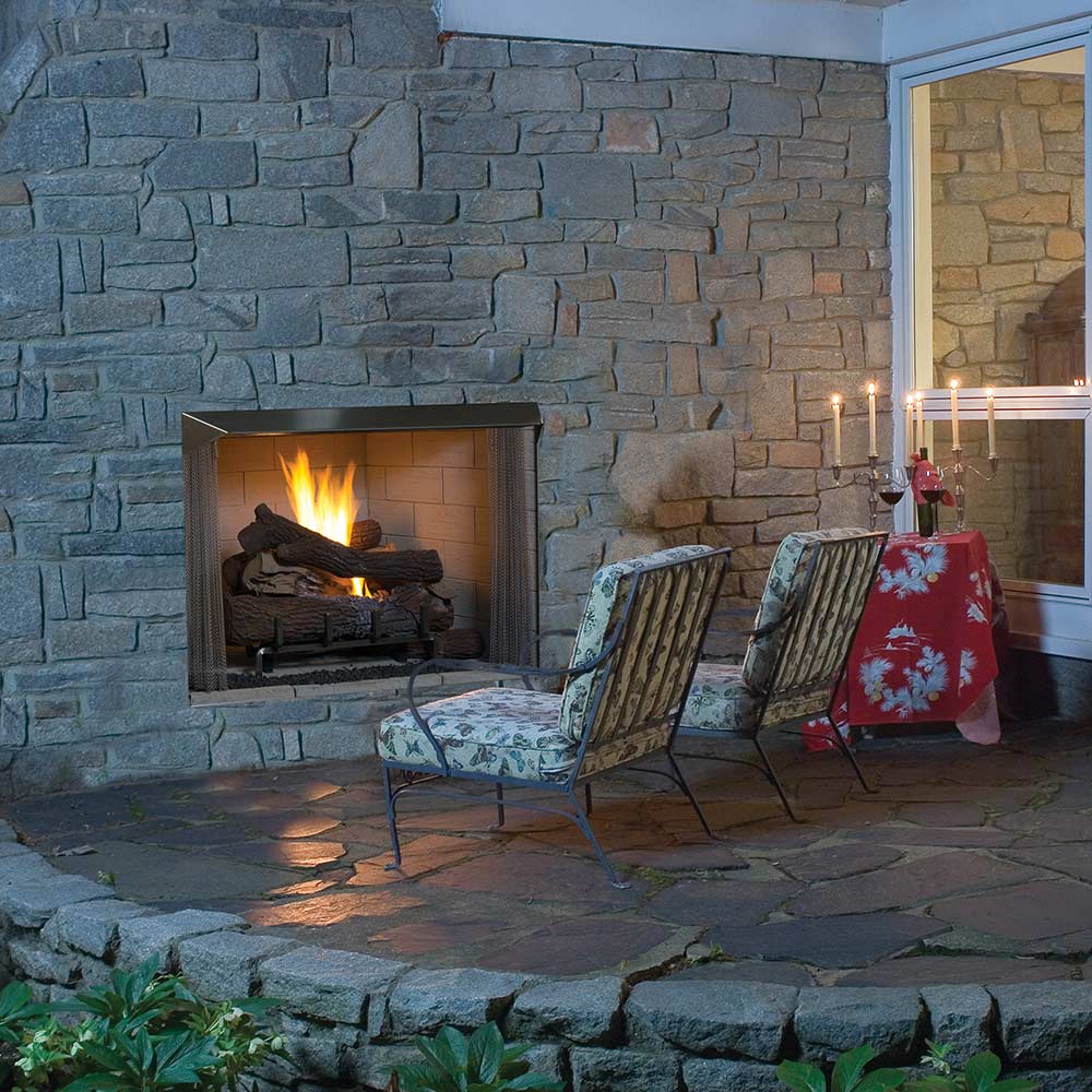 Outdoor vent-free firebox opening with burning logs set in a stone wall.