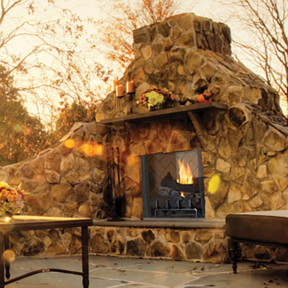 Outdoor gas firebox with stone surround and burning logs in front opening