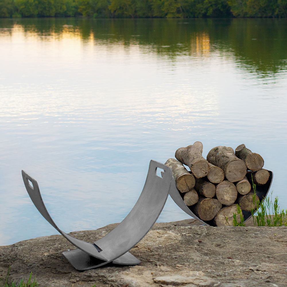 Stainless steel log rack with curved wings and U-shaped cradle on stone