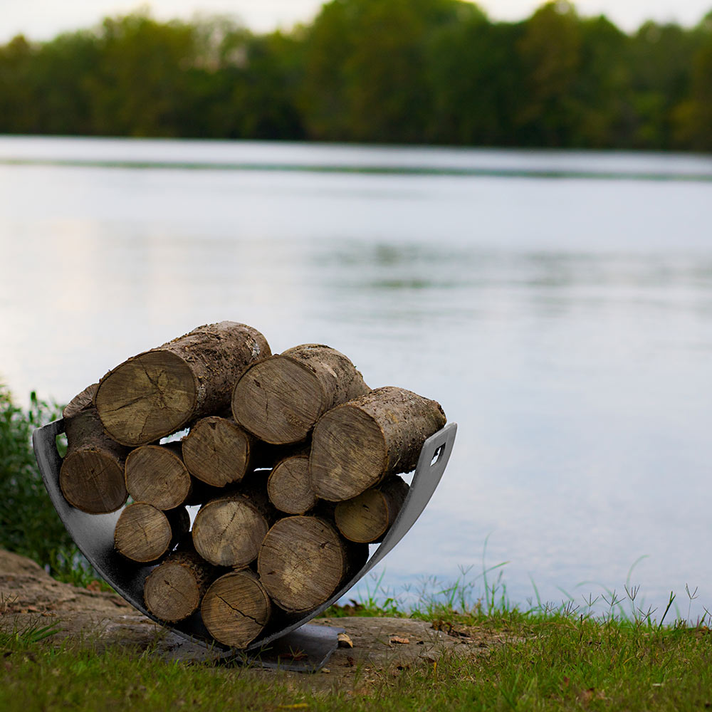 Stainless steel log rack holding firewood logs in a curved U-shaped cradle