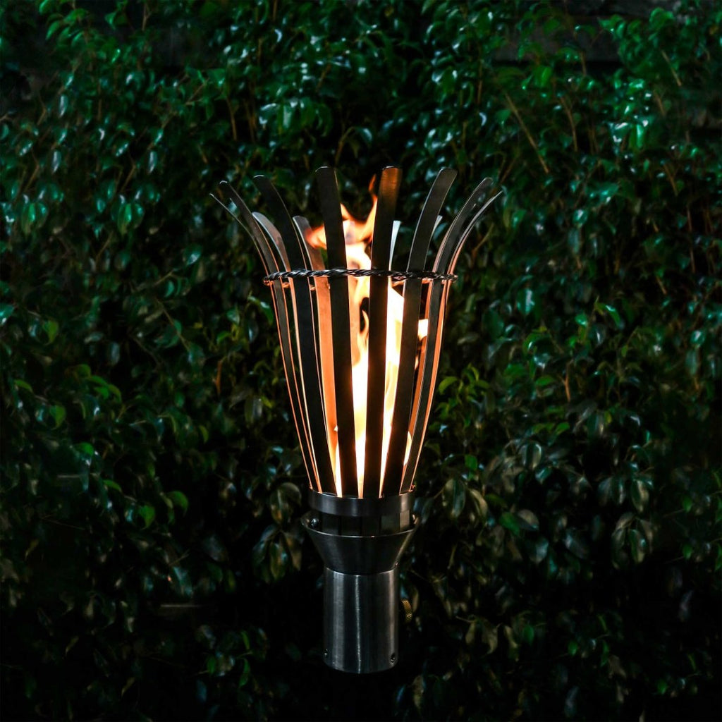 Outdoor torch with black metal stand and fan-shaped flame holder, lit
