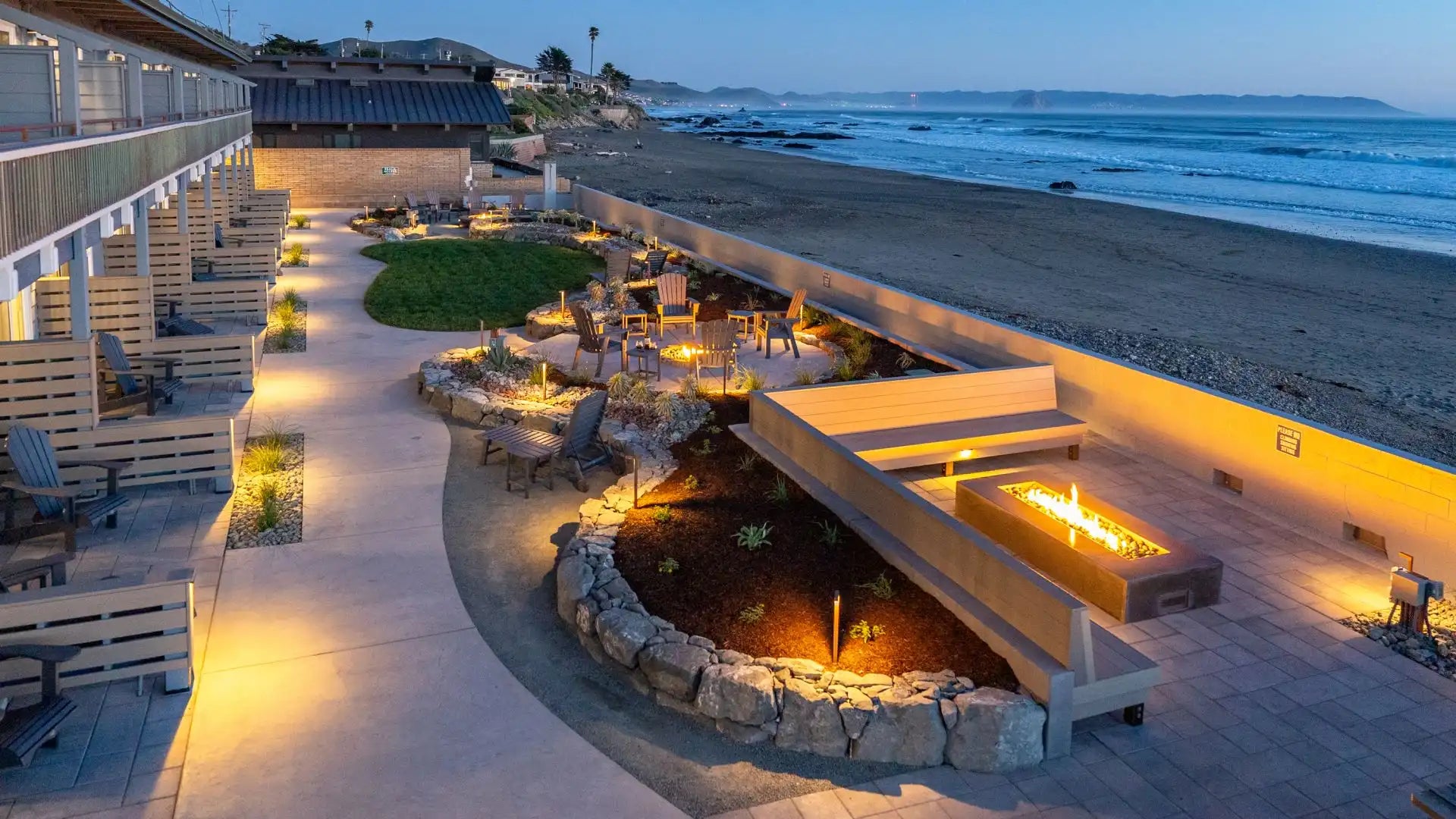 Outdoor seating area with fire pit by the beach at dusk