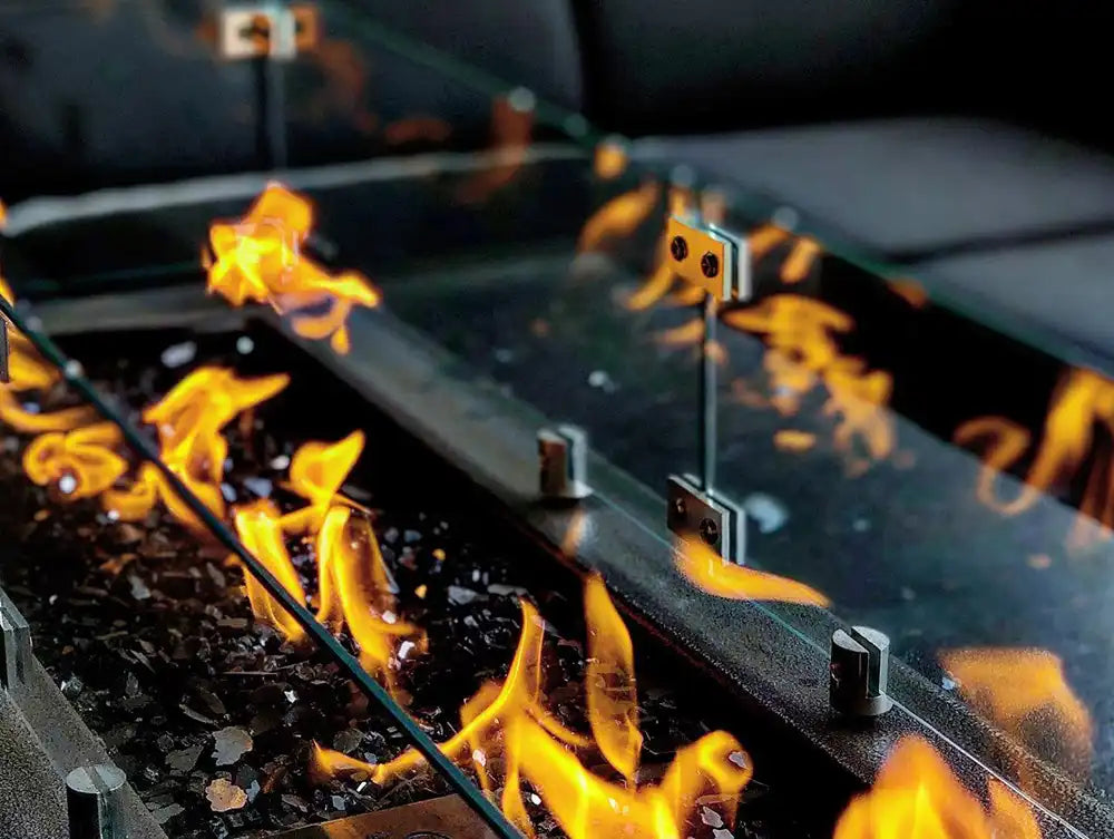 Close-up of a fire pit with flames reflecting on a glass surface