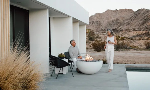 Man and woman standing beside a round fire pit on a desert patio — finance your outdoor fire pit with easy monthly payments