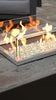 Closeup of gas flame in a gas fire pit reflecting off of clear fire glass