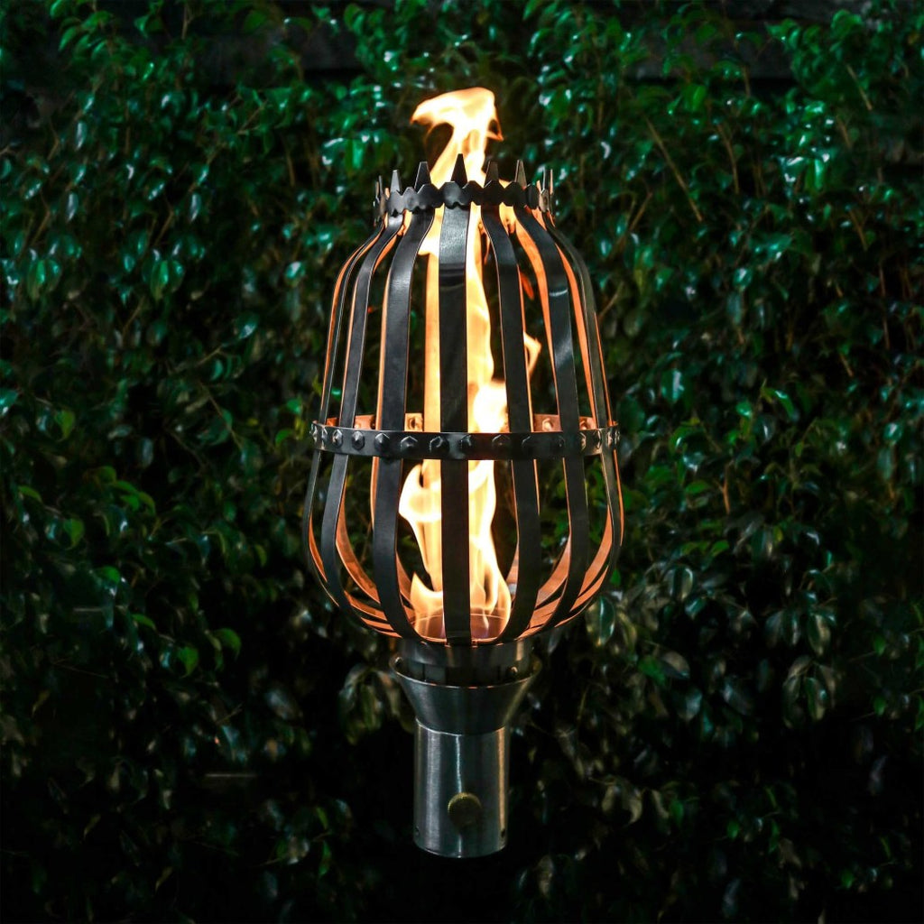 Outdoor torch with metal cage and burning flame on a stand